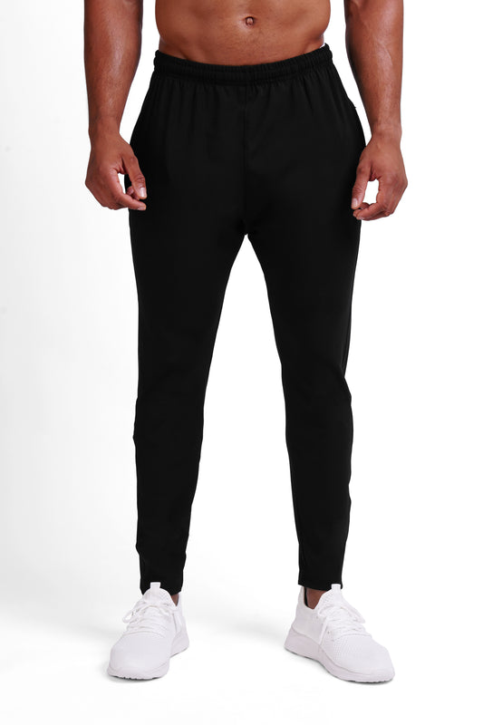 Man wearing black OG training pants from the front, tapered fit with elastic waistband and side pockets